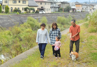 浅川の流れを見下ろしながら堤防を散歩する西沢英往さん（右）一家＝長野市豊野町豊野
