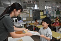 担任の先生から初めての通知表を受け取る児童