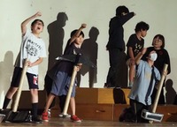 用水路を掘り進める小道具を持ち、音楽劇の練習をする児童ら