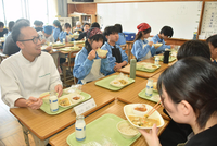 前田料理長（左）が考案した給食を食べる生徒たち