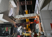 火花を散らし駐輪場（右）との連絡通路を切り離す作業が進む＝14日午前1時23分