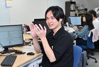 職場で同僚と話す五十嵐さん。高校時代に校則改正に取り組んだ経験が現在の糧になっている＝2日、東京都港区
