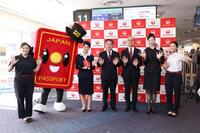 　日本航空と外務省が開いた記念イベントで「パスポくん」と写真に納まる関係者ら＝17日午後、羽田空港