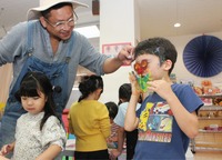 トモヤーツさん（左奥）と一緒にお面作りを楽しむ園児＝19日、須坂市のマリアこども園