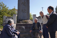 忠魂碑の前で語り合う遺族会の関係者
