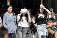 　強い日差しの下、大阪・道頓堀を歩く人たち＝21日午前
