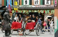 　東京・浅草で人力車を楽しむ外国人観光客。周辺では多くの訪日客が行き交っていた＝7月